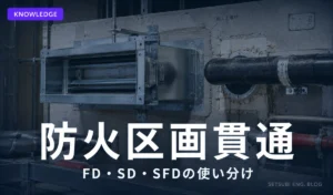 防火区画の壁をダクトと配管が貫通している建設現場のクローズアップ。FD（防火ダンパー）と耐火充填材が写る
