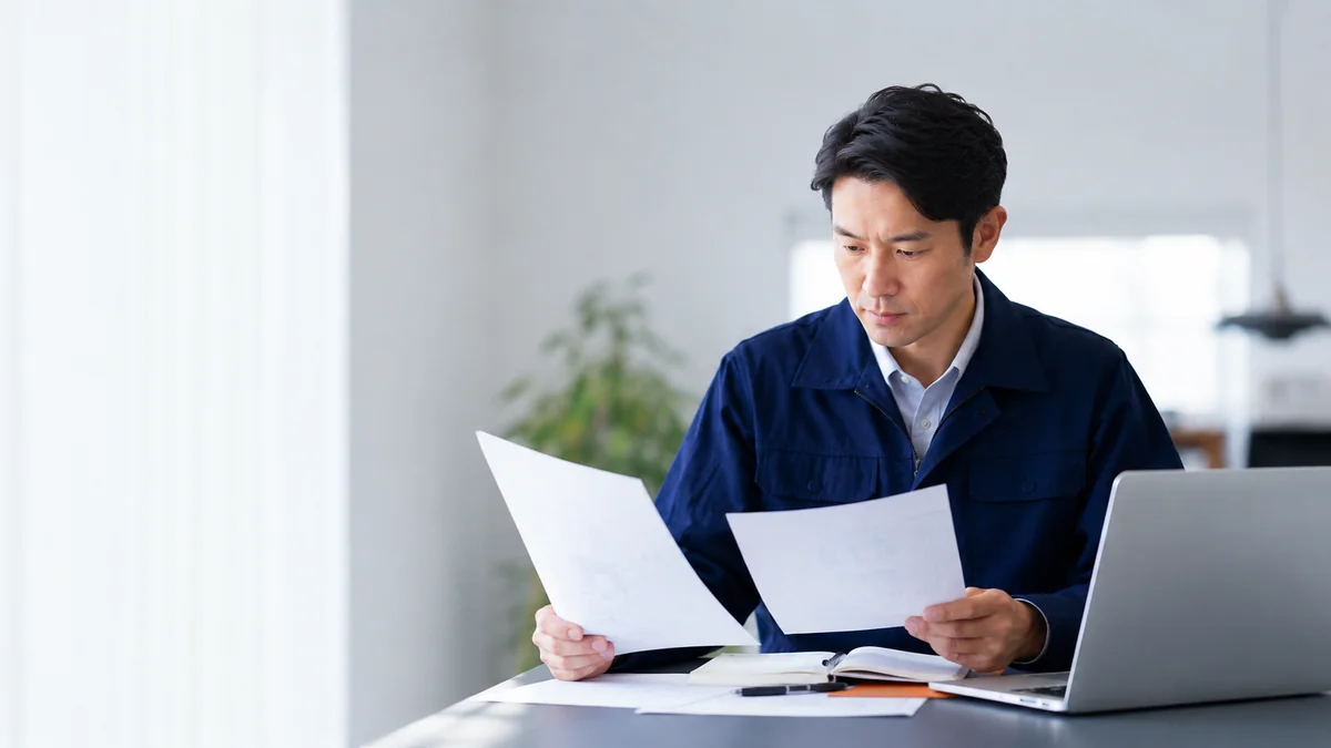 書類を見比べて転職エージェントを選ぶ設備エンジニア