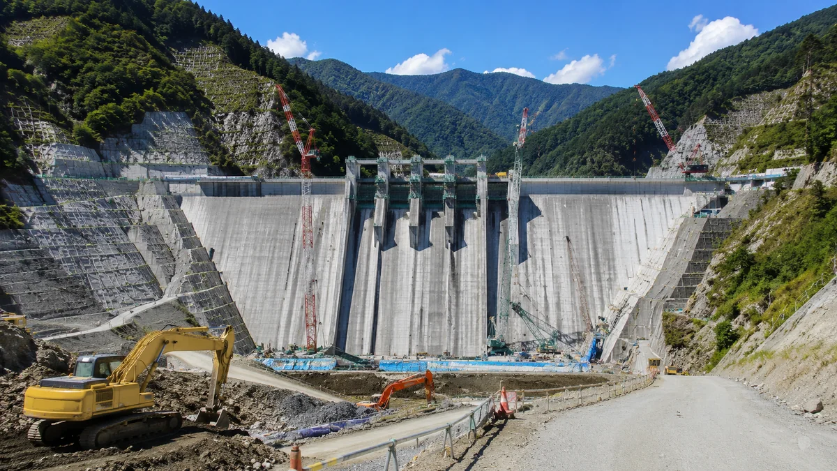 山あいのコンクリートダム建設現場と重機。大規模土木に強いゼネコンのイメージ