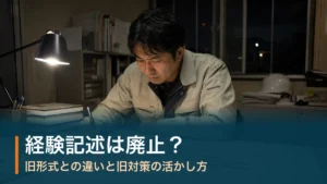 夜の現場事務所で第二次検定の答案を書く施工管理技術者。1級管工事の経験記述は廃止され、旧形式との違いと旧対策の活かし方を解説